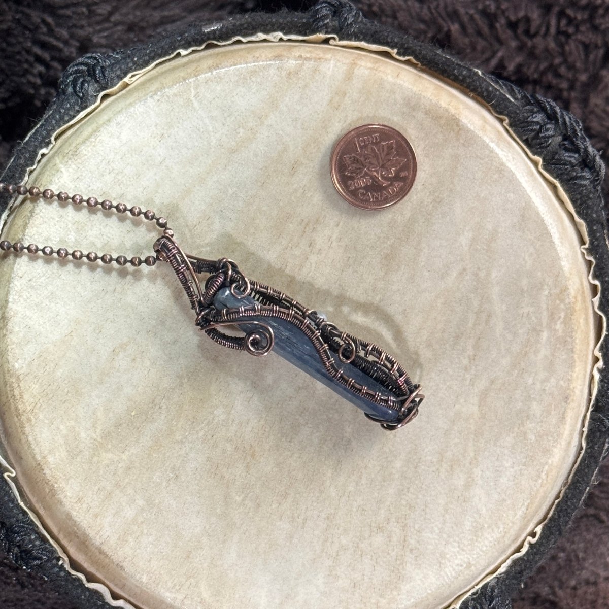 Side one of a reversible polished blue kyanite necklace with patinated copper spirals, woven borders and a streamlined unisex design.