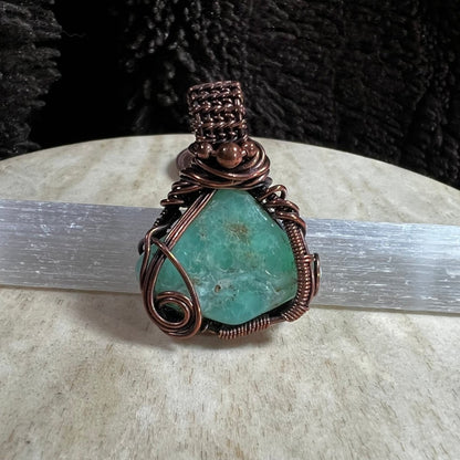 Close-up of green Chrysoprase crystal pendant wrapped in artisan copper wire.