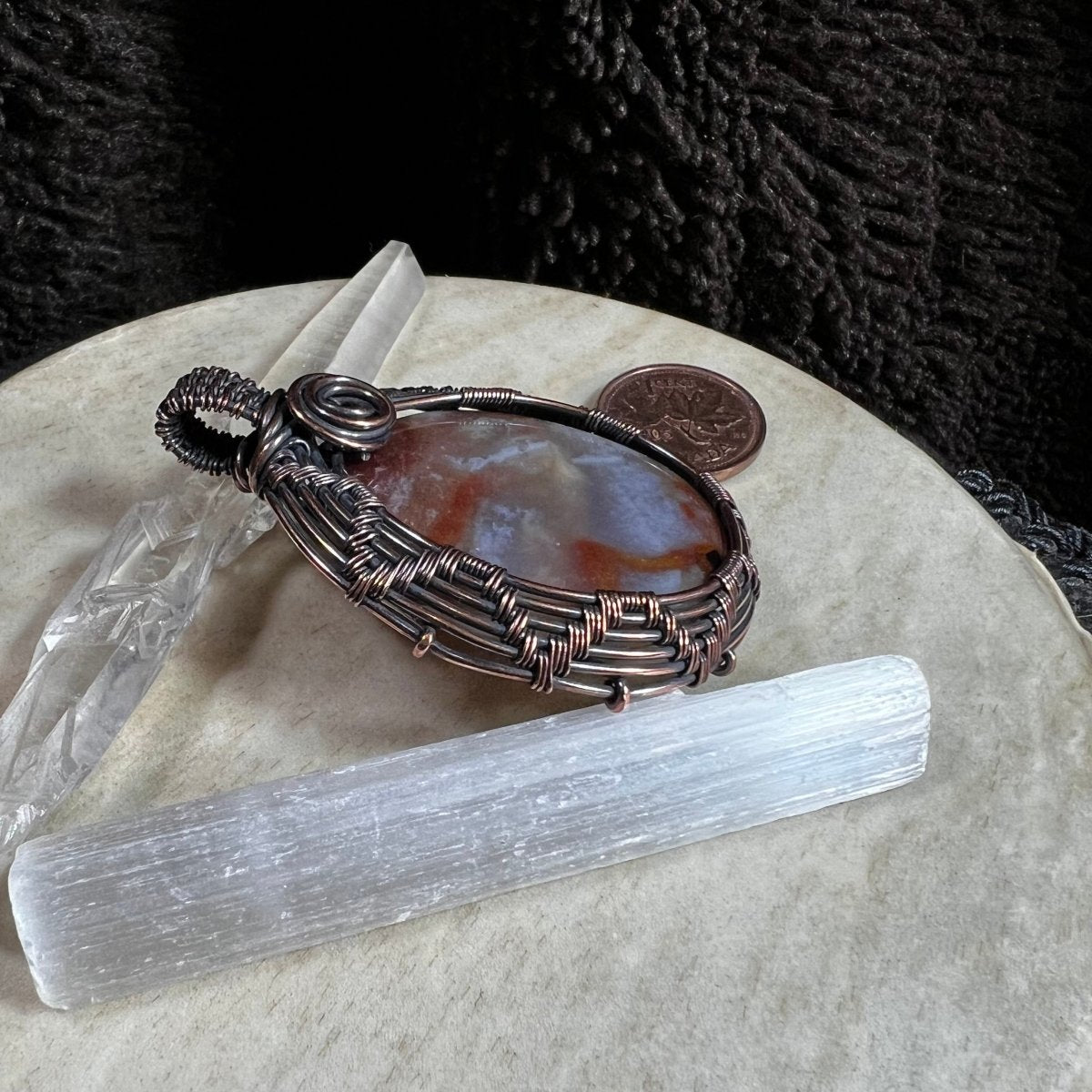 Side view of copper-wrapped agate pendant highlighting structured wirework