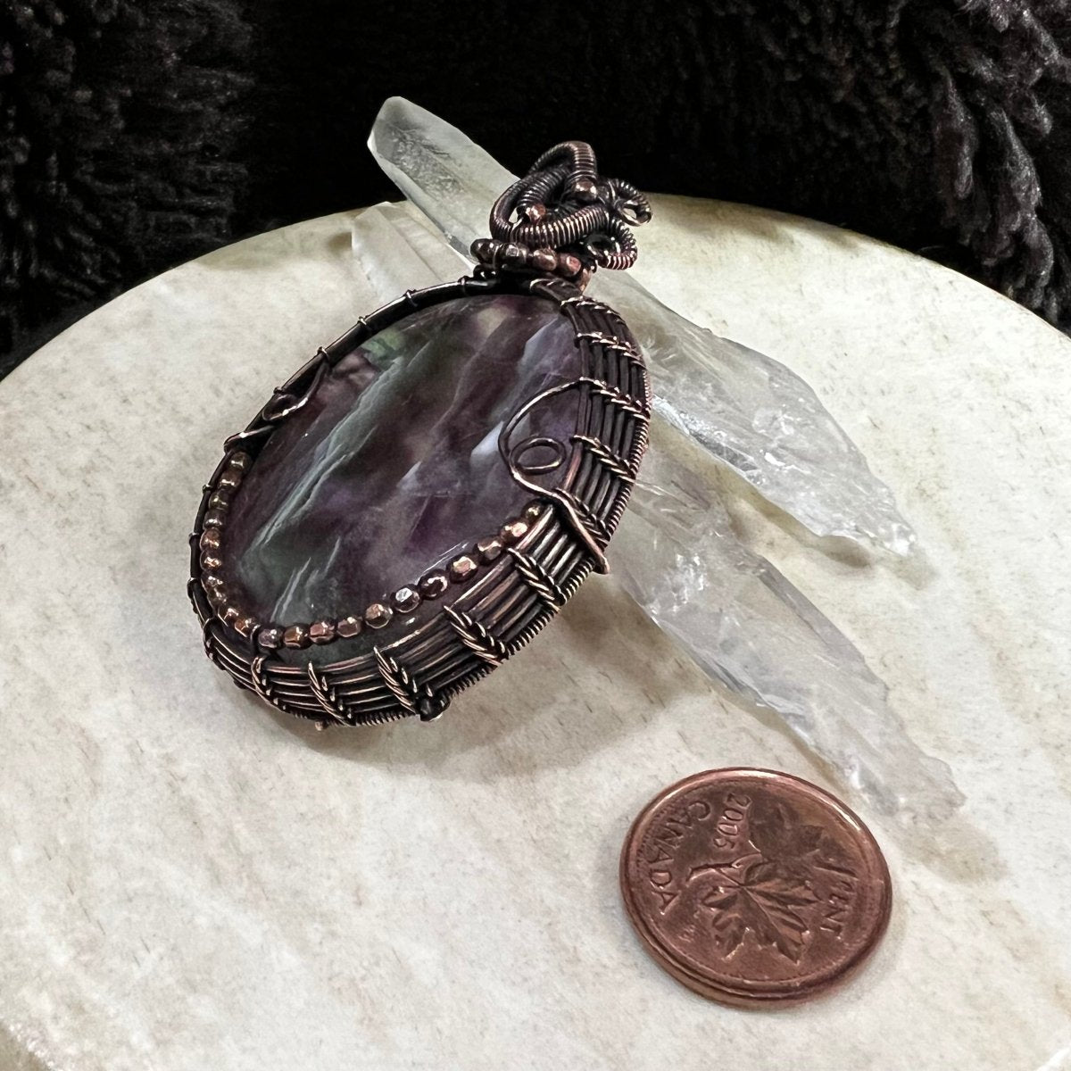 Side angle of fluorite pendant highlighting structured copper wrap and faceted bead accents