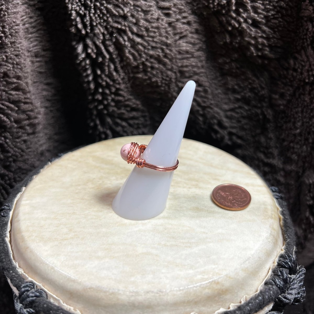 White cone-shaped jewelry stand with a ring on a textured surface