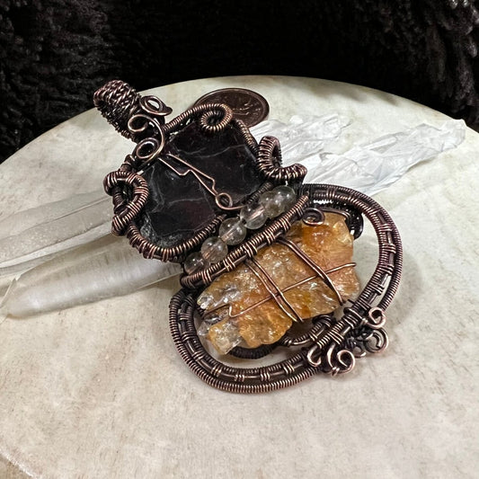 Garnet slice pendant wrapped in patinated copper with raw sunstone and citrine accents, rich dark and golden contrast