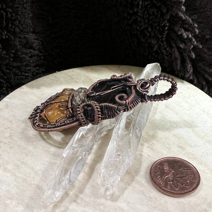 Garnet and sunstone pendant displayed with quartz points and Canadian penny for scale and contrast in lighting