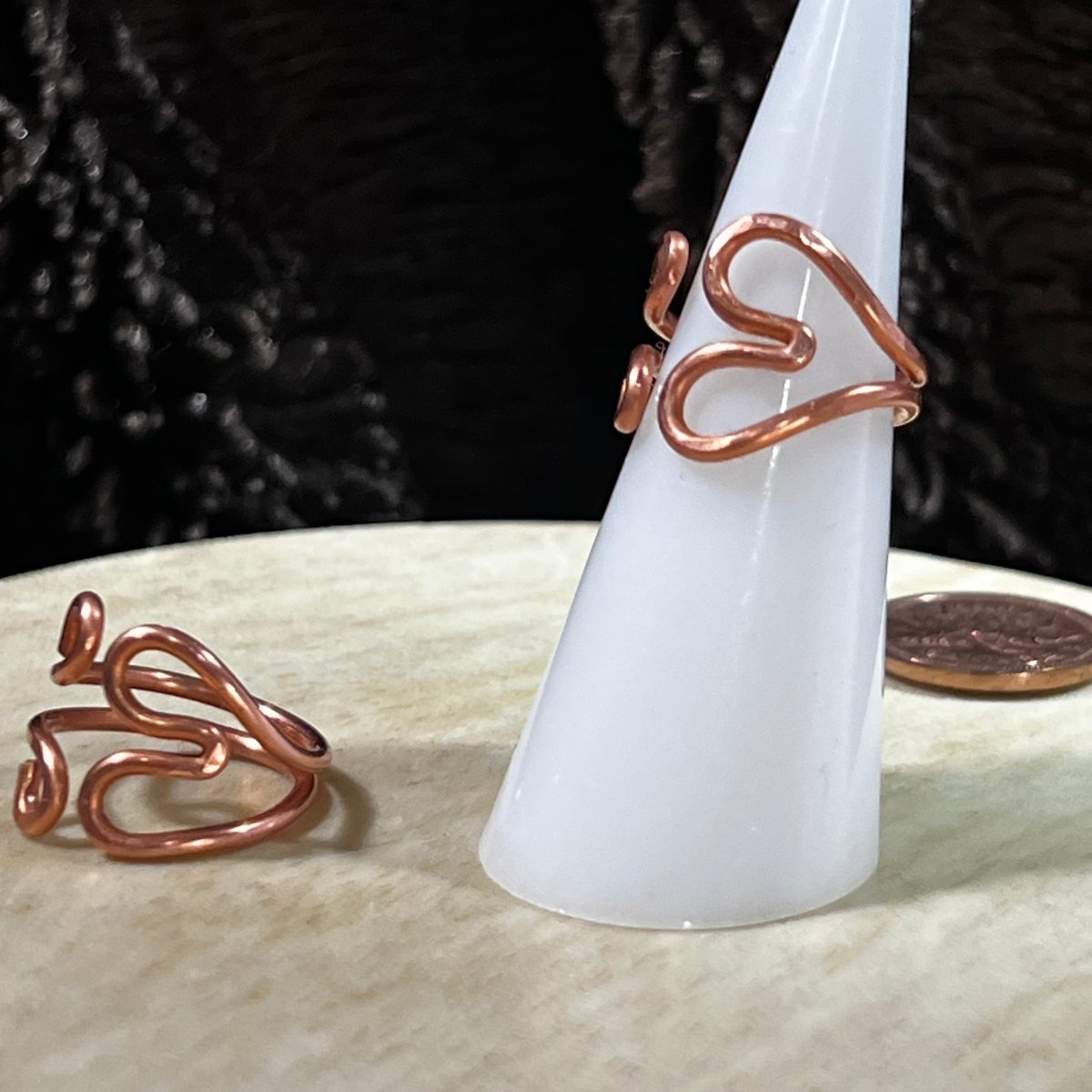 Reclaimed copper wire heart-shaped ring on a white cone with a black background