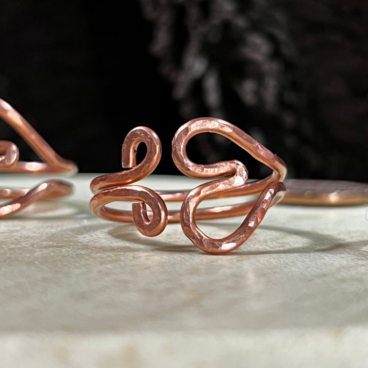Reclaimed copper wire heart-shaped ring on a white surface with a black background