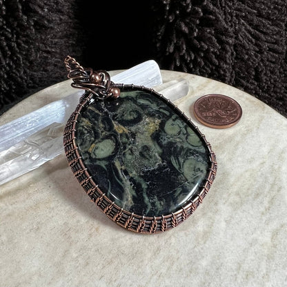 Kambaba jasper pendant with deep green and black orb patterns in copper wrap