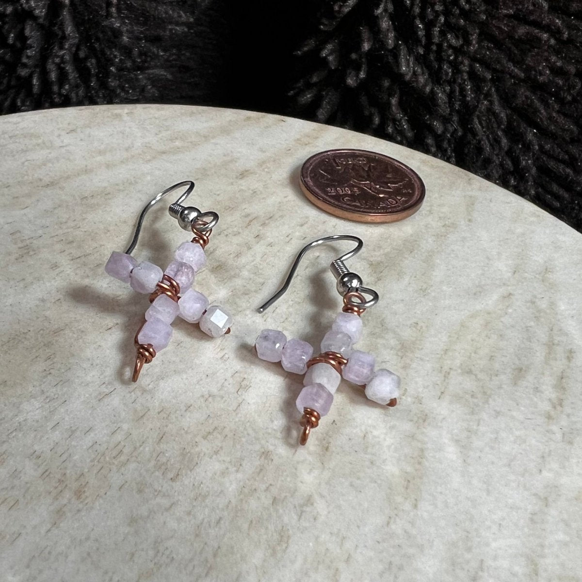 Beaded cross earrings on a marble surface with a penny for scale.