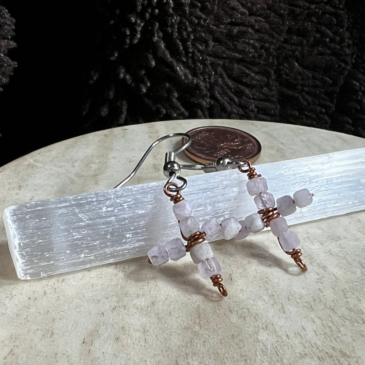 Beaded earrings on a selenite crystal with a coin for scale
