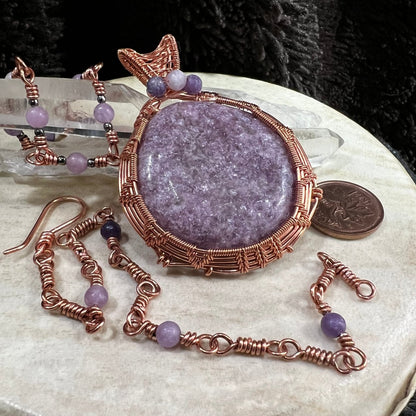 Lepidolite  jewelry set with pendant and two bracelets on a neutral surface next to a Canadian penny for scale.