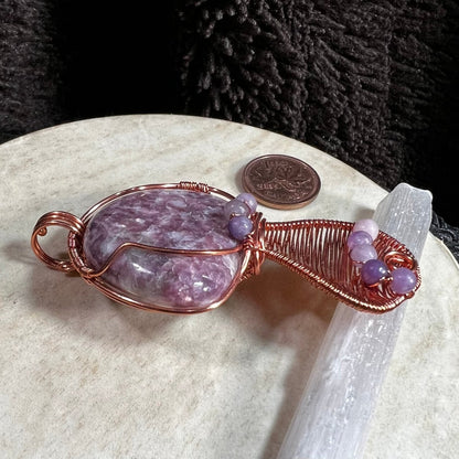 Lepidolite mushroom pendant displayed with selenite crystal next to a Canadian penny for contrast and scale