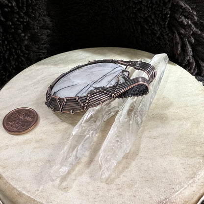 Side view of copper-wrapped pendant highlighting structured wire frame and patina finish