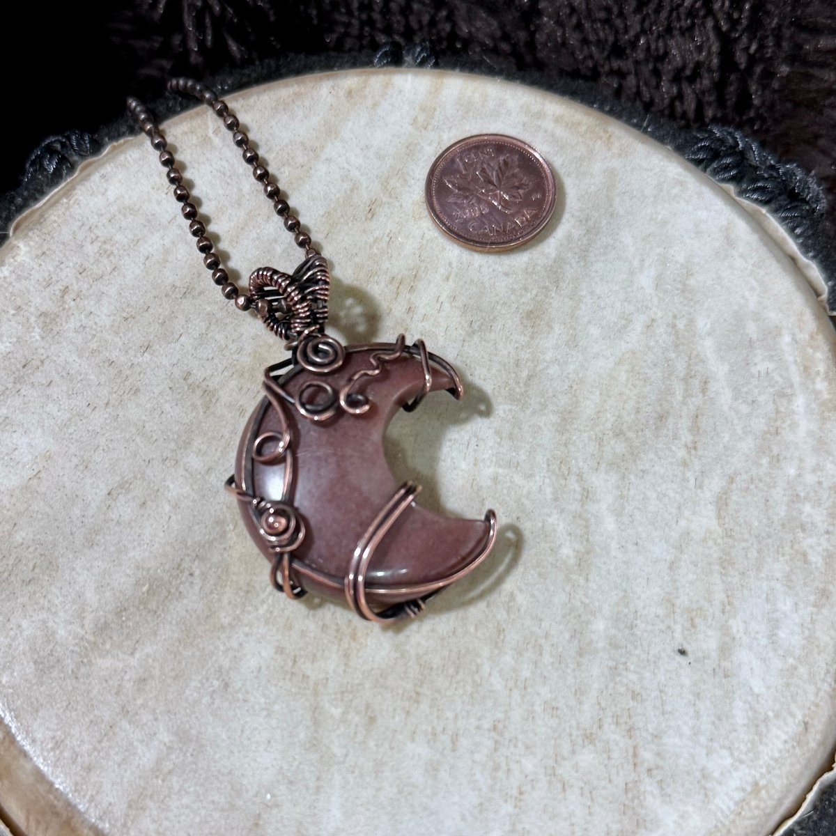 Front view of a crescent-shaped Purple Aventurine pendant decorated with copper spirals and wrapped in patinated reclaimed copper.