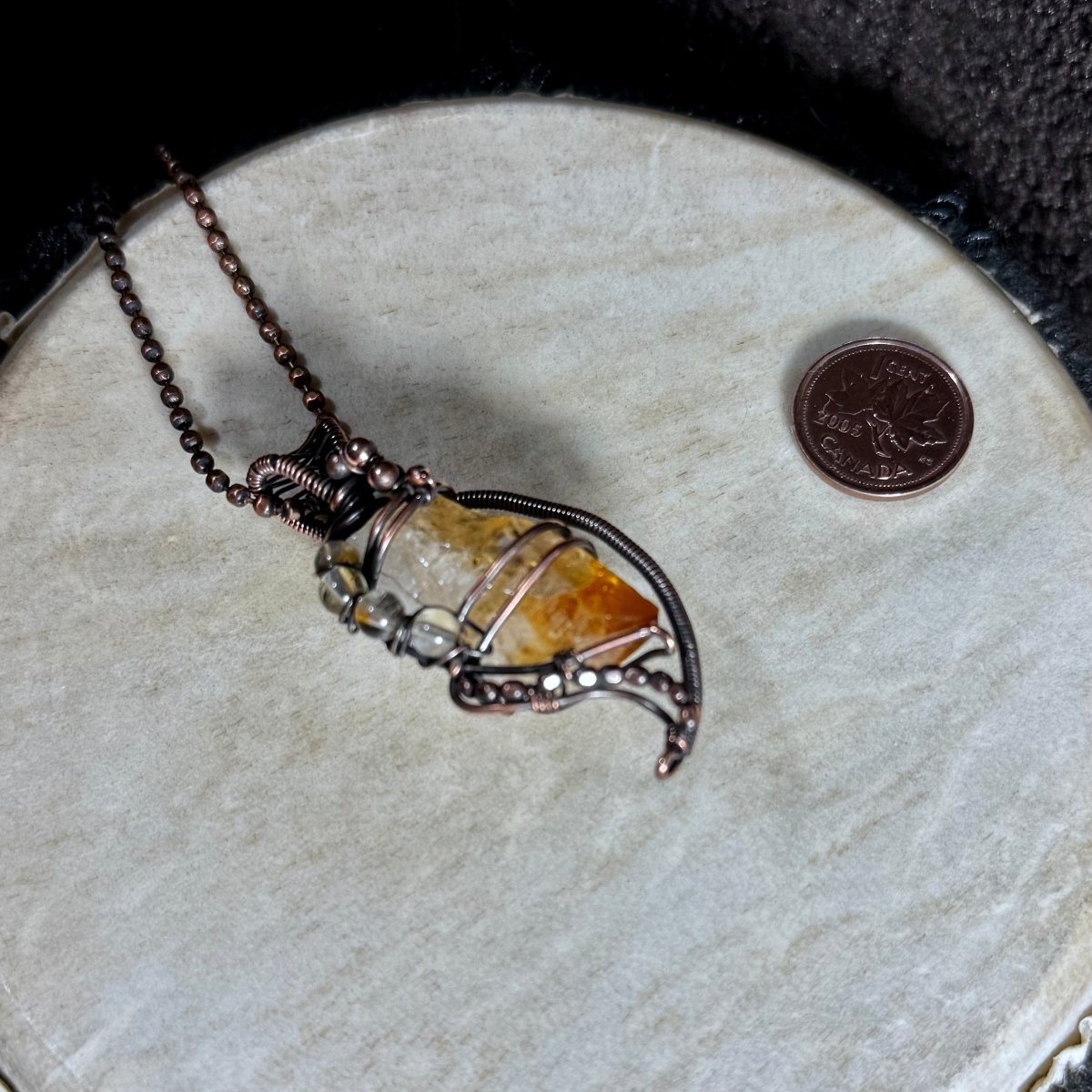 Front view of the Citrine Abundance Talisman showing its raw crystal point, sweeping copper frame and 20-inch faceted ball chain.