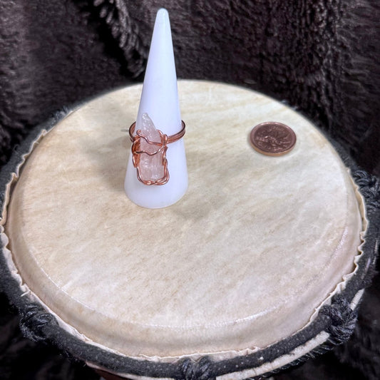 Front view of a raw pale pink rose quartz crystal wrapped in reclaimed copper as a handmade size 8.5 statement ring.