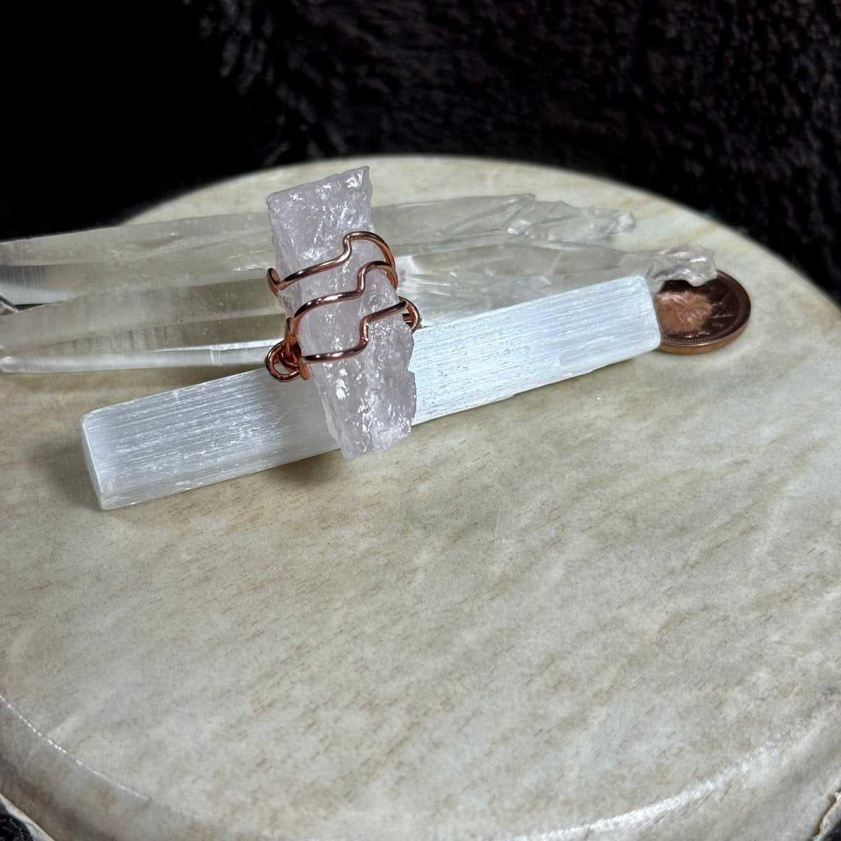 Front view of a chunky raw rose quartz crystal held by three flowing bands of reclaimed copper in a handmade size 8.5 ring.