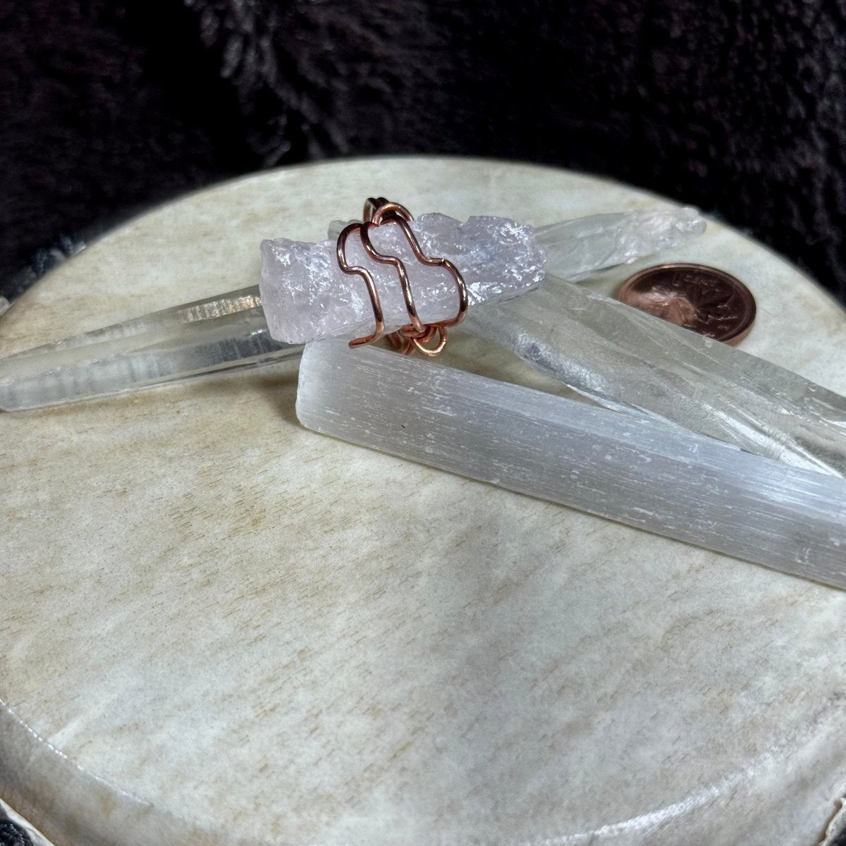 Detailed view of a pale pink raw rose quartz crystal crossed by protective reclaimed copper lines in a one-of-a-kind ring.