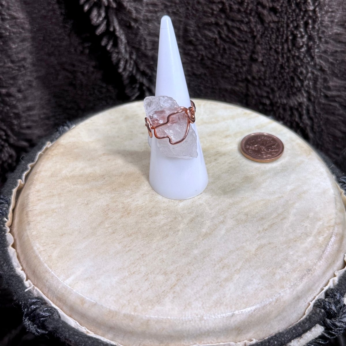 Front view of a raw pale pink rose quartz crystal wrapped in reclaimed copper as a handmade size 6 spiral ring.