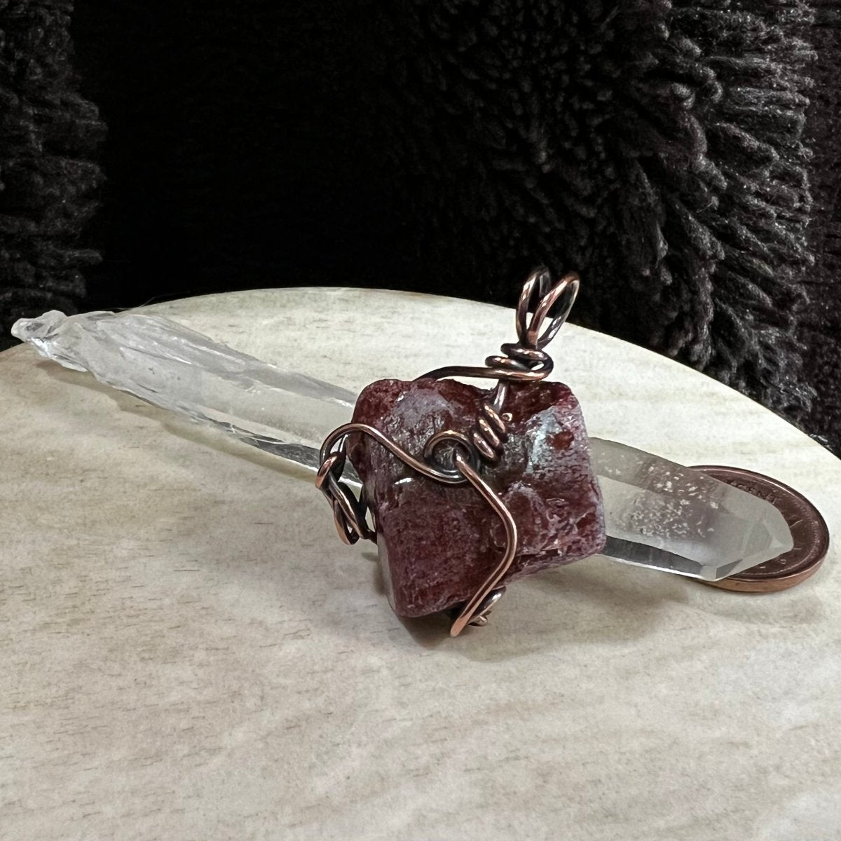 red calcite pendant wrapped in reclaimed copper with natural rough texture, handmade grounding crystal necklace on neutral background