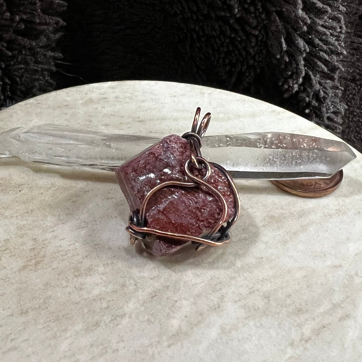red calcite pendant wrapped in reclaimed copper with natural rough texture, handmade grounding crystal necklace on neutral background
