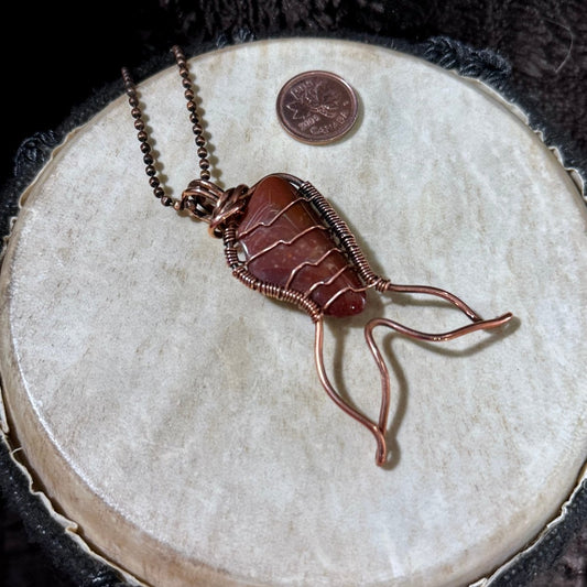 Handmade Red Jasper Mermaid Tail pendant wrapped in reclaimed copper, featuring a rich red natural gemstone with subtle banding and a flowing mermaid tail design.
