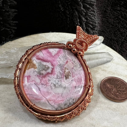 rhodochrosite pendant wrapped in reclaimed copper with pink and cream natural patterns, handmade heart healing crystal necklace on neutral background