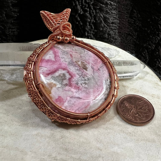 rhodochrosite pendant wrapped in reclaimed copper with pink and cream natural patterns, handmade heart healing crystal necklace on neutral background
