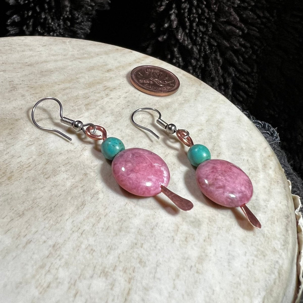 Pink and turquoise beaded earrings on a white surface with a coin for scale.