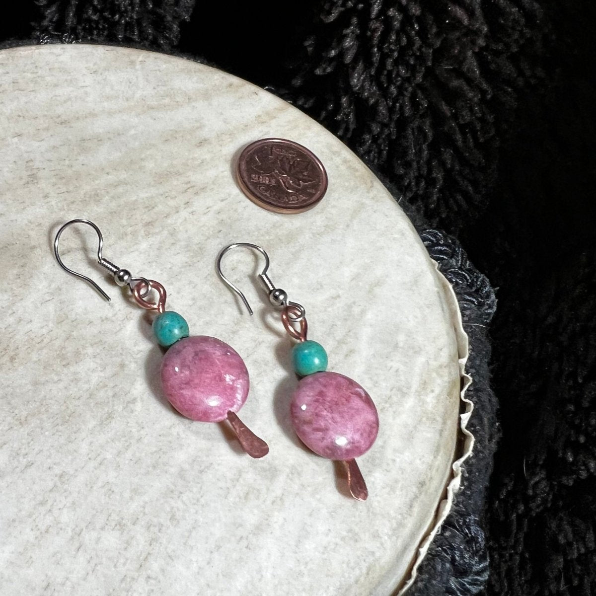 Pink beaded earrings with turquoise accents on a white surface.