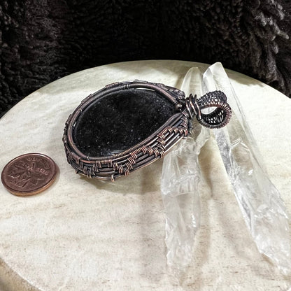 Silver sheen obsidian pendant wrapped in patinated copper with deep black polished surface and subtle reflective glow