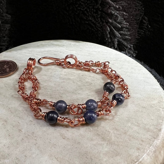 sodalite double strand bracelet with three 6mm blue beads per strand and reclaimed copper wire links, handmade clarity bracelet on a beige background