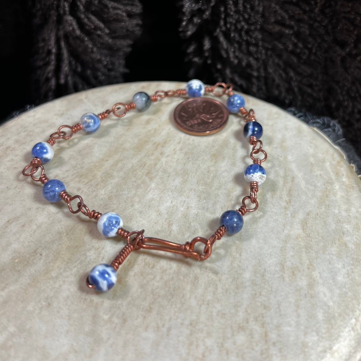 Close-up of sodalite gemstone bracelet with reclaimed copper wire wrapping, artisan handmade jewelry