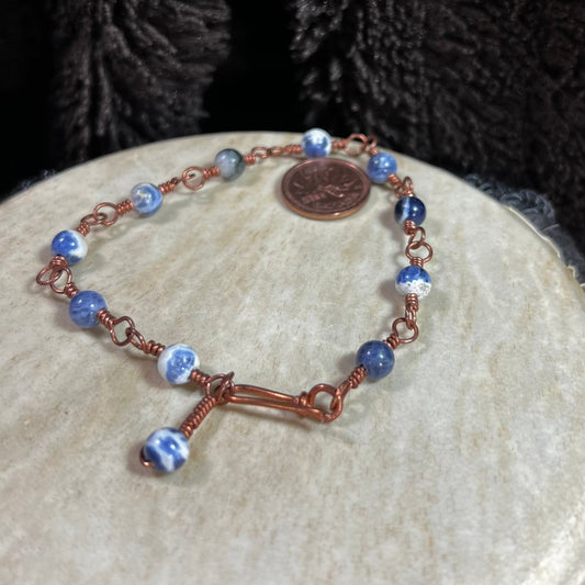 Close-up of sodalite gemstone bracelet with reclaimed copper wire wrapping, artisan handmade jewelry