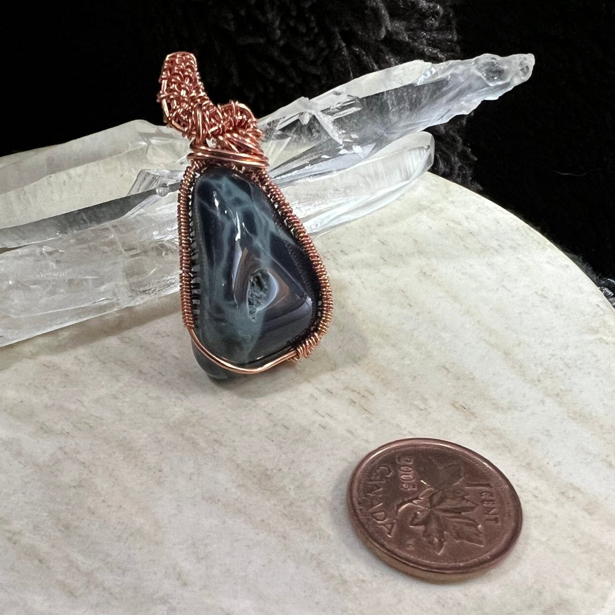 Spiderweb obsidian pendant wrapped in reclaimed copper with dark glossy black stone and natural void detail, handmade protection crystal necklace on neutral background