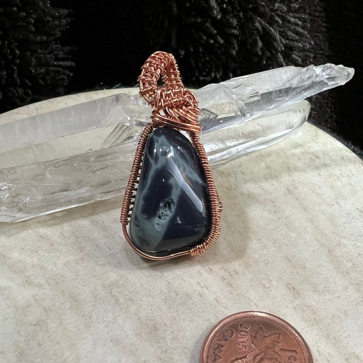 Spiderweb obsidian pendant wrapped in reclaimed copper. A dark glossy black and gray stone and natural void detail, handmade protection crystal necklace on neutral background