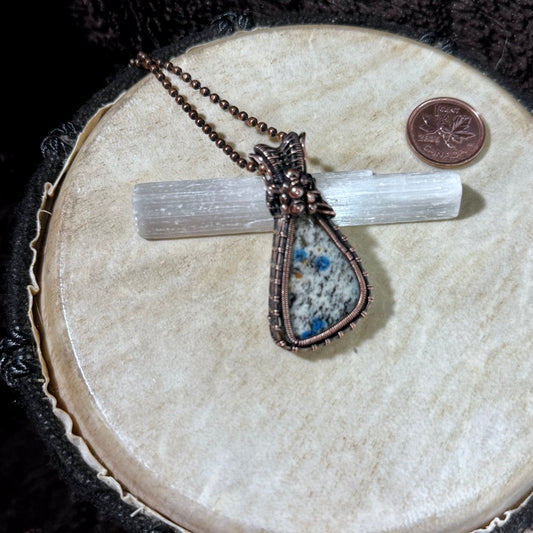 Front view of Summit Oracle, a triangular K2 Jasper cabochon with vivid blue azurite spots, hand-wrapped in dark patinated copper on a 16-inch chain.