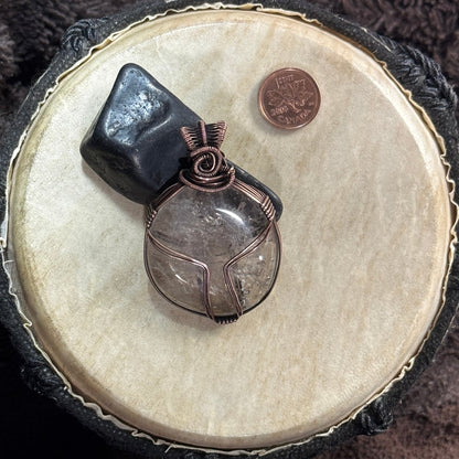 Reversible smoky quartz and patinated copper pendant styled against black shungite, with a Canadian penny included for scale.