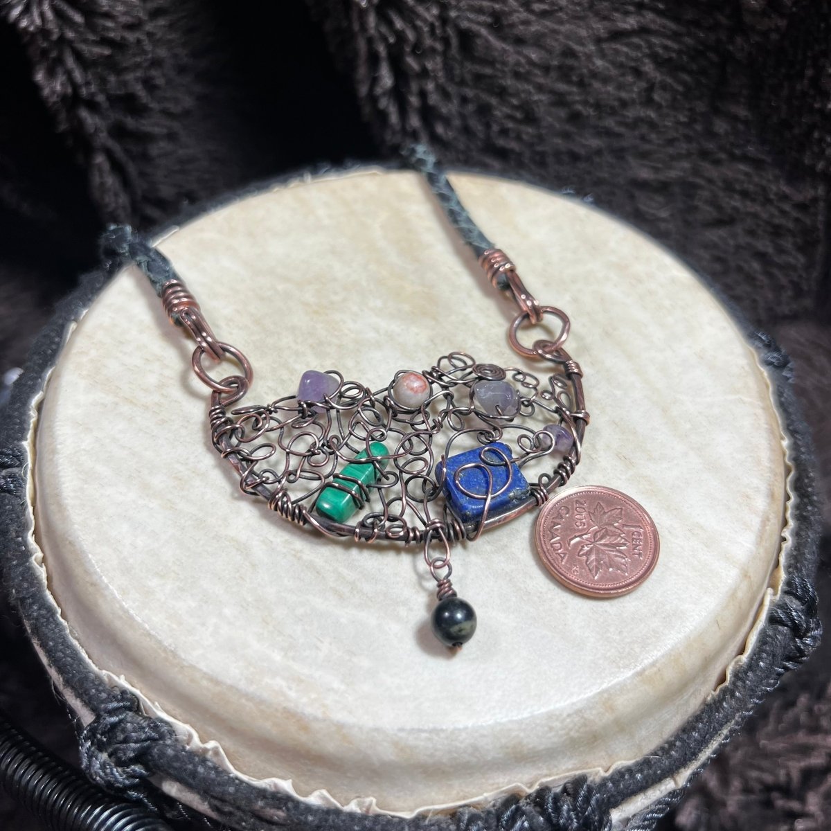 Necklace with a half-moon shaped pendant and colorful beads on a textured surface