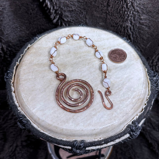 Open white moonstone bracelet with individually wire-wrapped stones, a large hammered spiral focal and handmade hook closure in reclaimed copper.