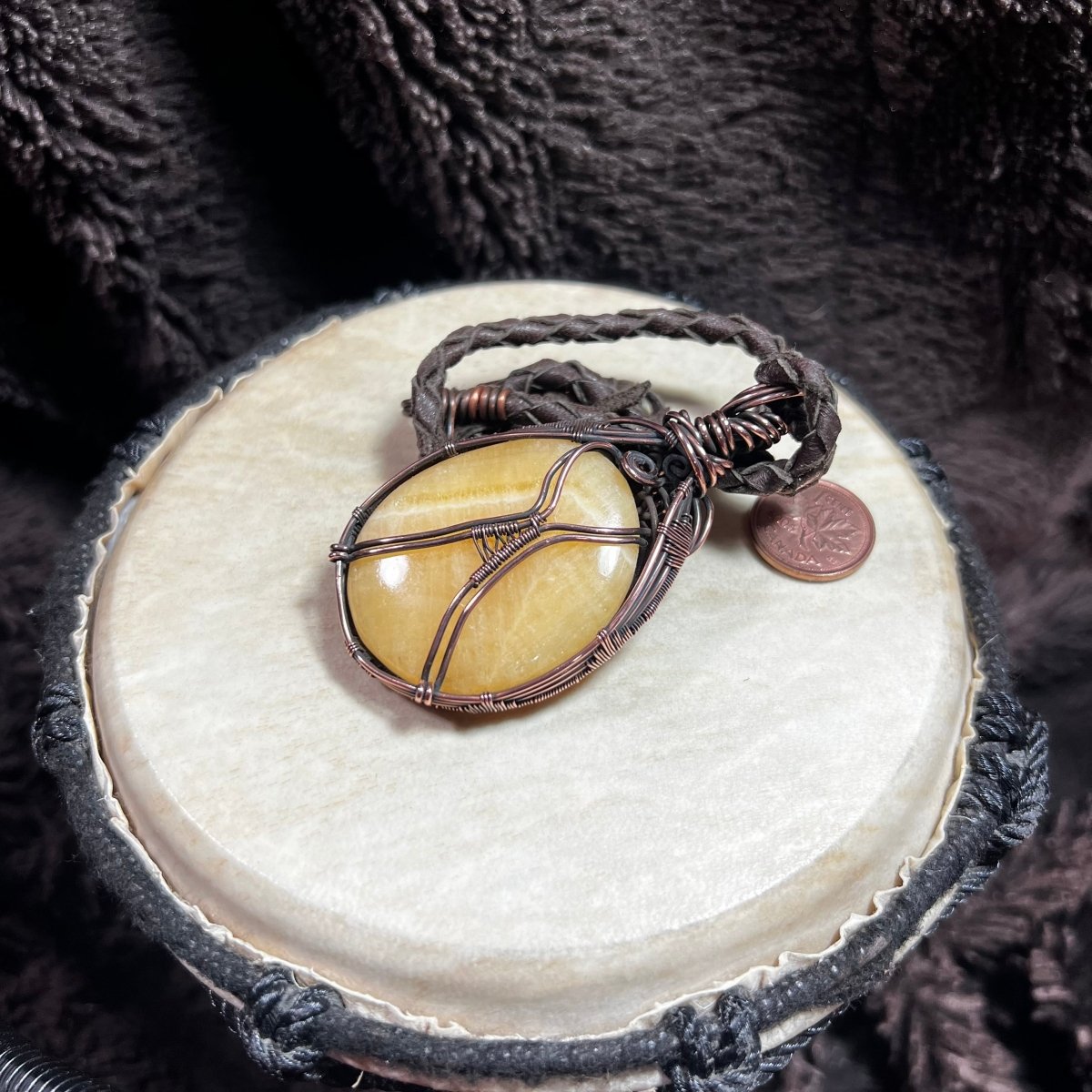 Back view of a necklace with a yellow stone pendant on a textured surface