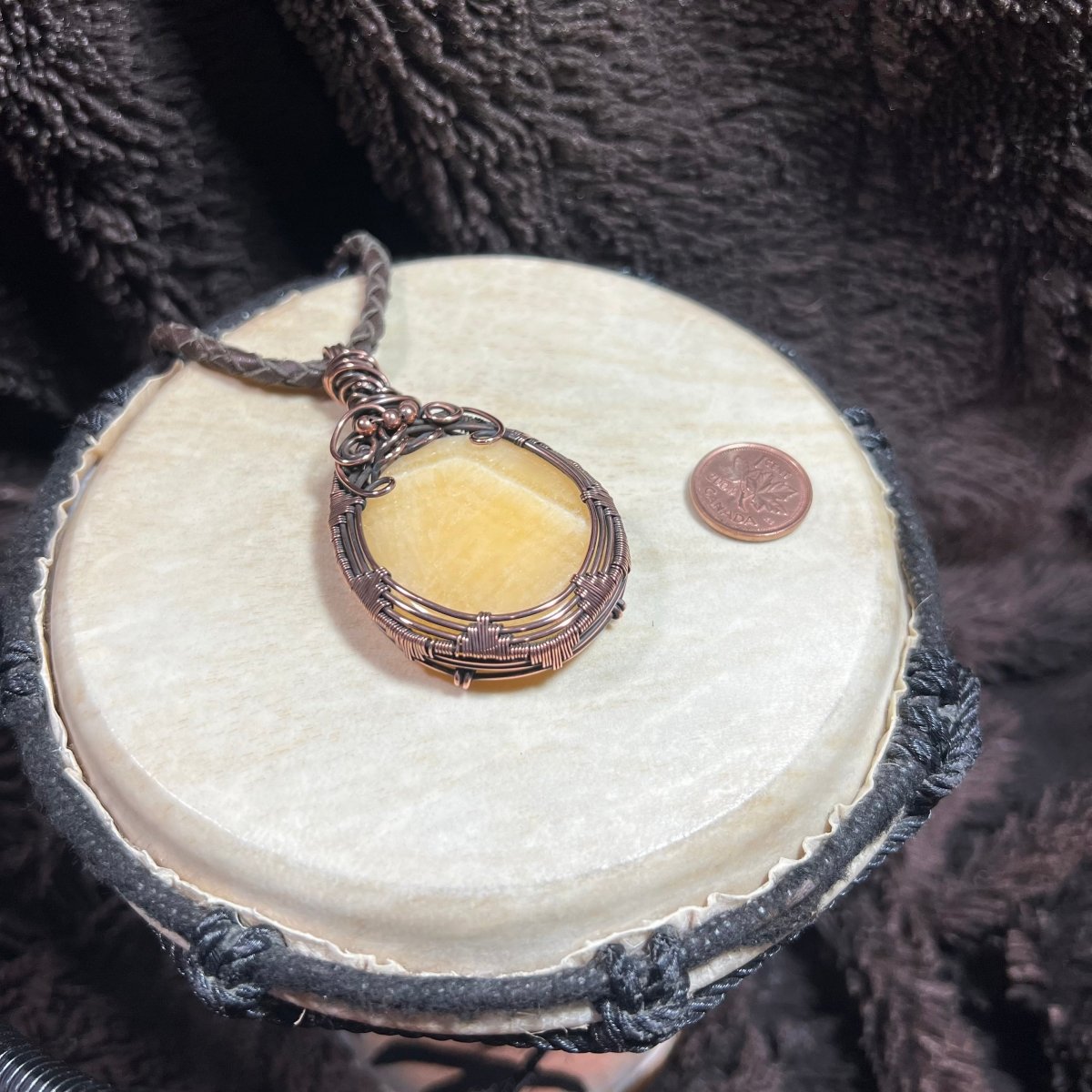 Necklace with a yellow stonependant on a round white stone with a dark textured background