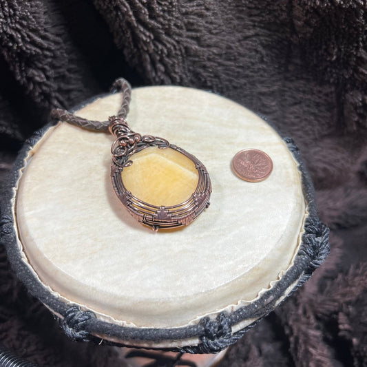 Necklace with a yellow stonependant on a round white stone with a dark textured background