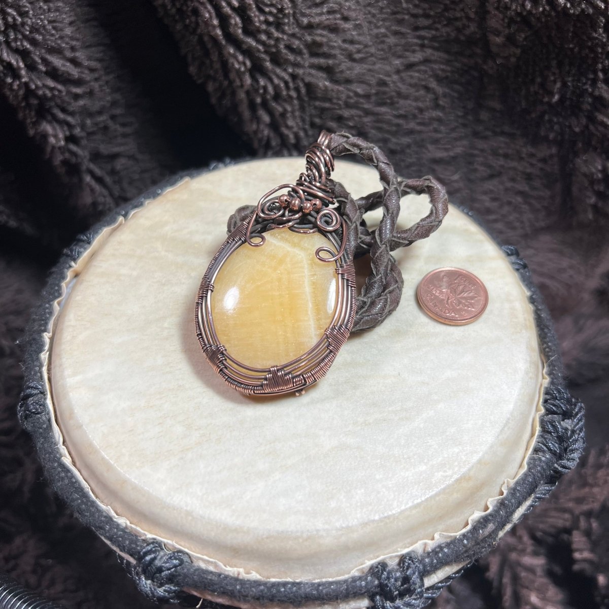 Necklace with a yellow stone pendant on a round white surface with a dark textured background