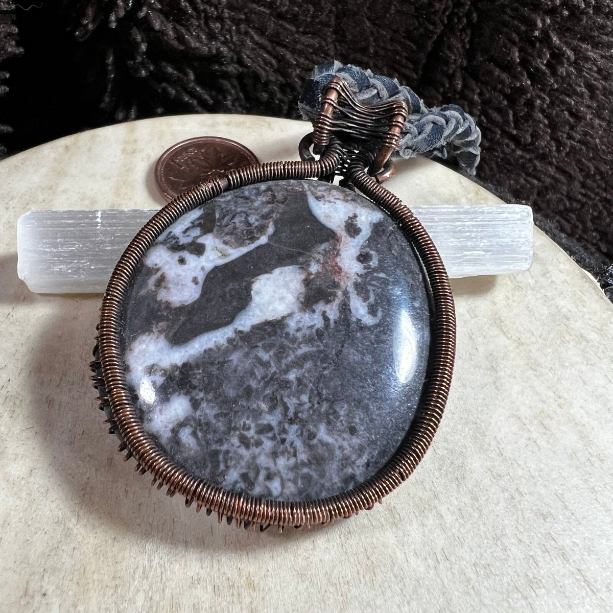 Close-up of round Zebra Stone gemstone pendant showing natural black and white banding.