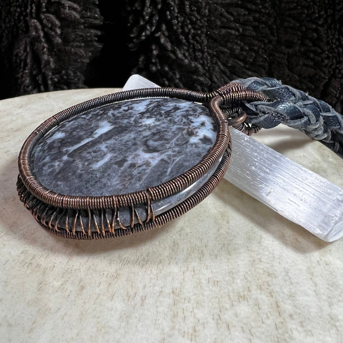 Handmade Zebra Stone pendant wrapped in reclaimed copper wire displayed on a selenite wand.