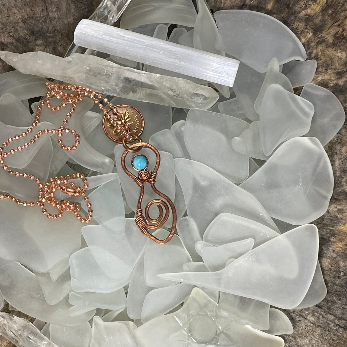 Spiral Goddess Necklace nestled in a bed of white sea glass